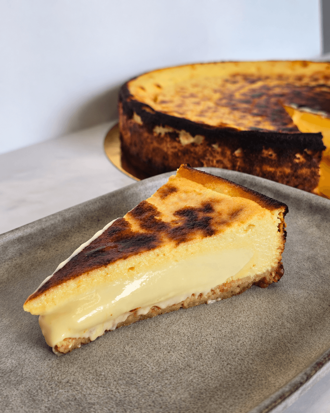 Ein Stück San Sebastian Cheesecake mit cremigem Kern und goldbrauner Oberfläche auf einem Teller